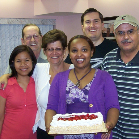 Happy members.  One of the members is holding a cake